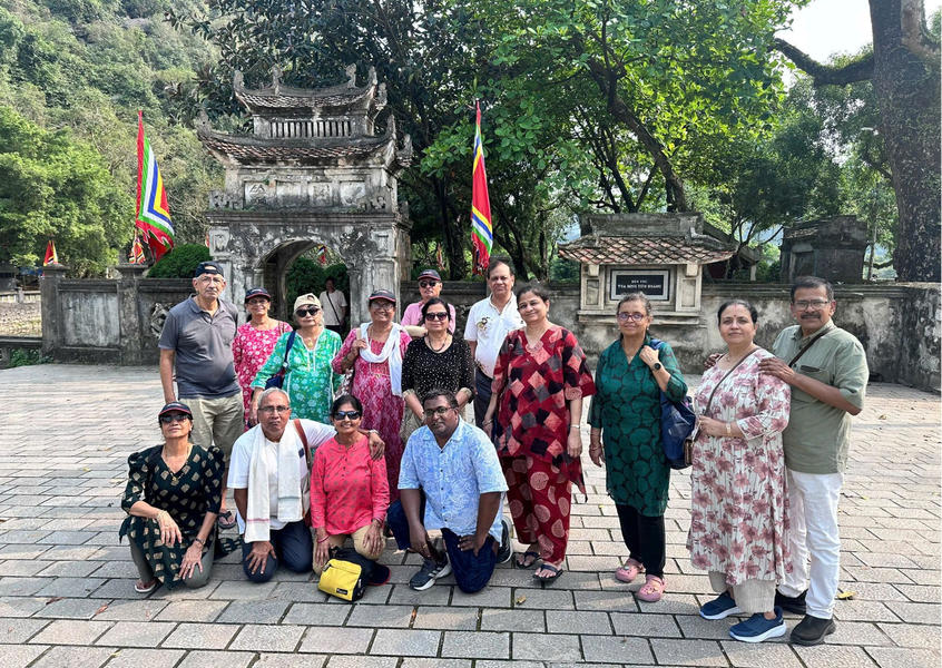 A group of Indian visitors poses in front of a traditional ancient stone gate