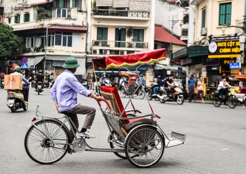 Cyclo rickshaw rider on a busy street in Hanoi Old Quarter