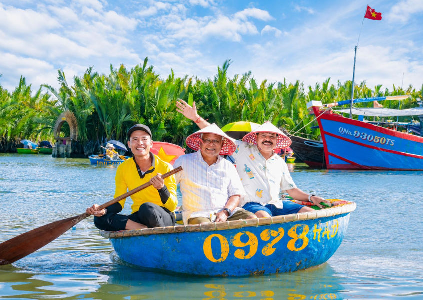 Indian tourists wearing conical hats (Non La) enjoying a traditional bamboo basket boat tour at Cam Thanh coconut forest in Hoi An