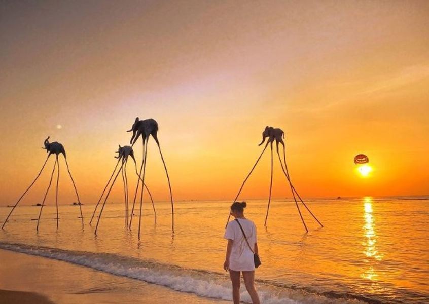 Woman watching sunset with elephant sculptures at Phu Quoc beach