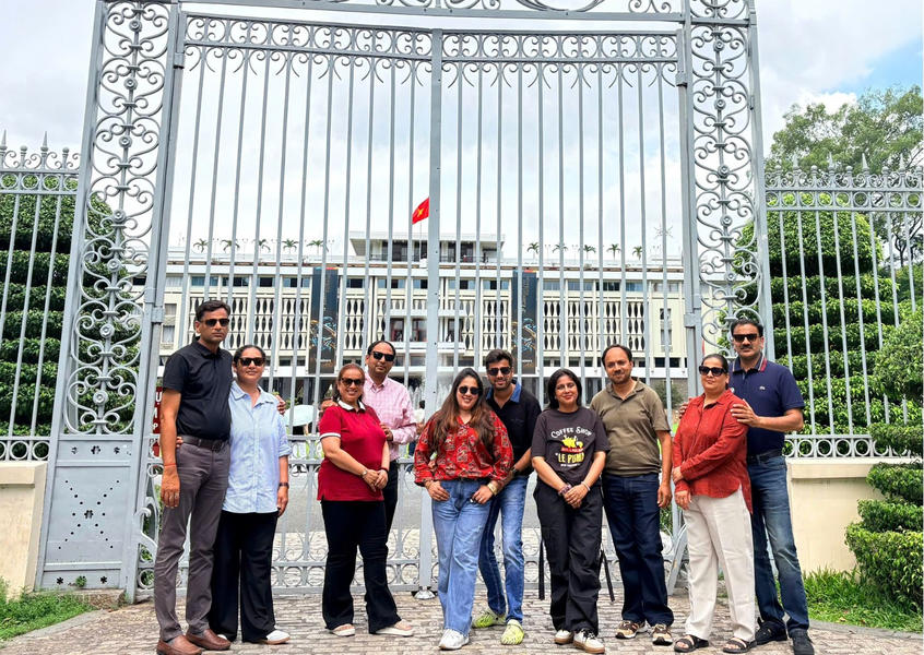 Group of tourists posing in front of the ornate iron gates of Reunification Palace (Independence Palace) in Ho Chi Minh City