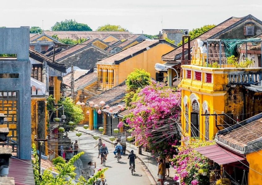 Yellow merchant houses and cyclists on a street in Hoi An Ancient Town