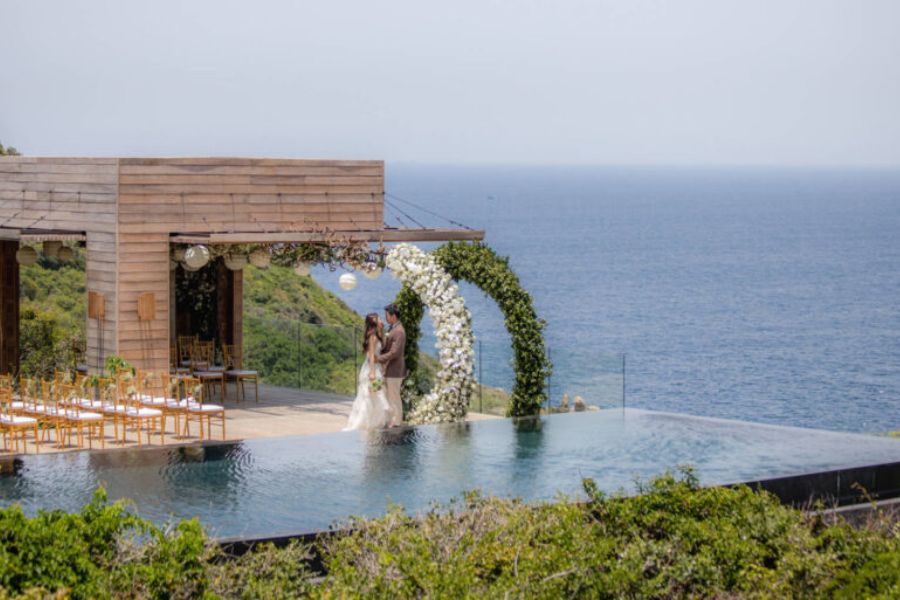 Couple embraces under floral arch at Amanoi infinity pool