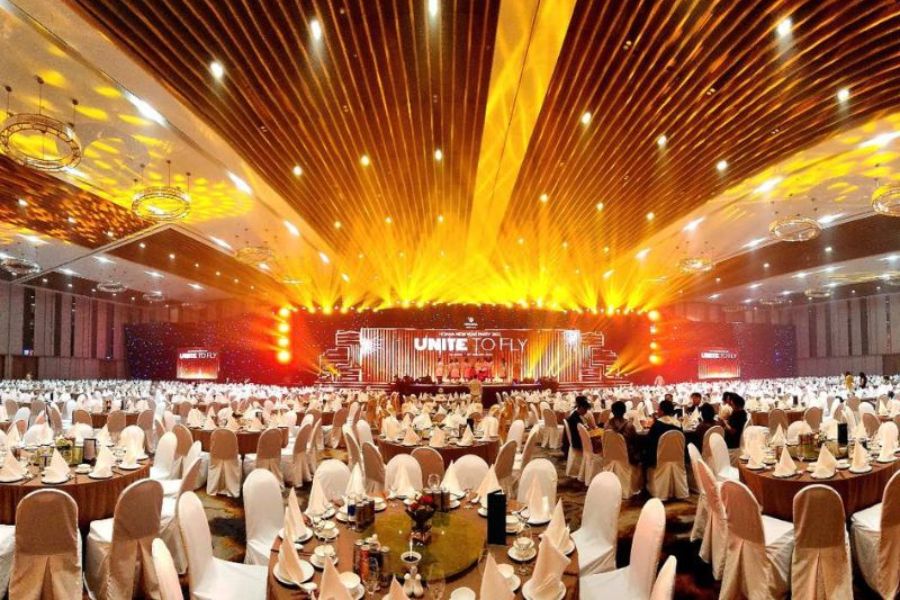Corporate gala dinner with dramatic gold stage lighting and round tables