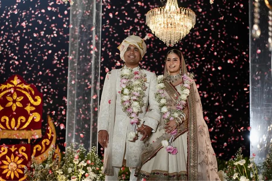 Indian newlyweds under rose petal shower at reception stage