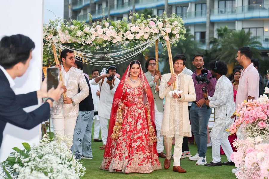 Indian bride and groom walk under floral canopy at Danang resort