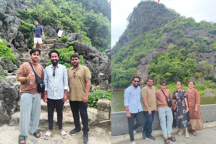 Travelers climbing stone steps near Mua Cave limestone cliffs