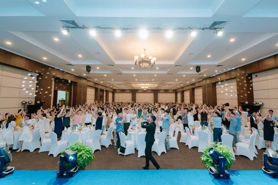 Group of corporate delegates cheering together in a conference ballroom