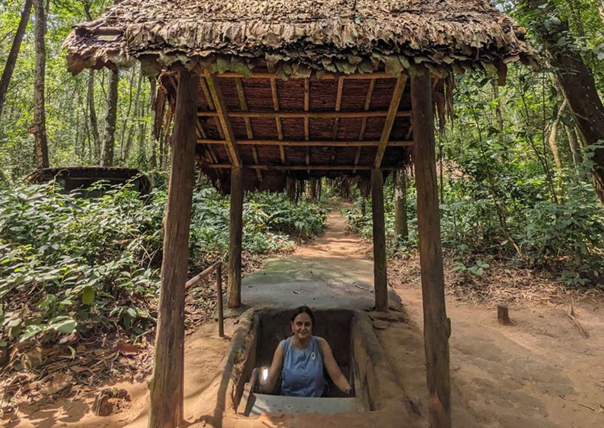 Traveler sitting inside a Cu Chi Tunnels entrance