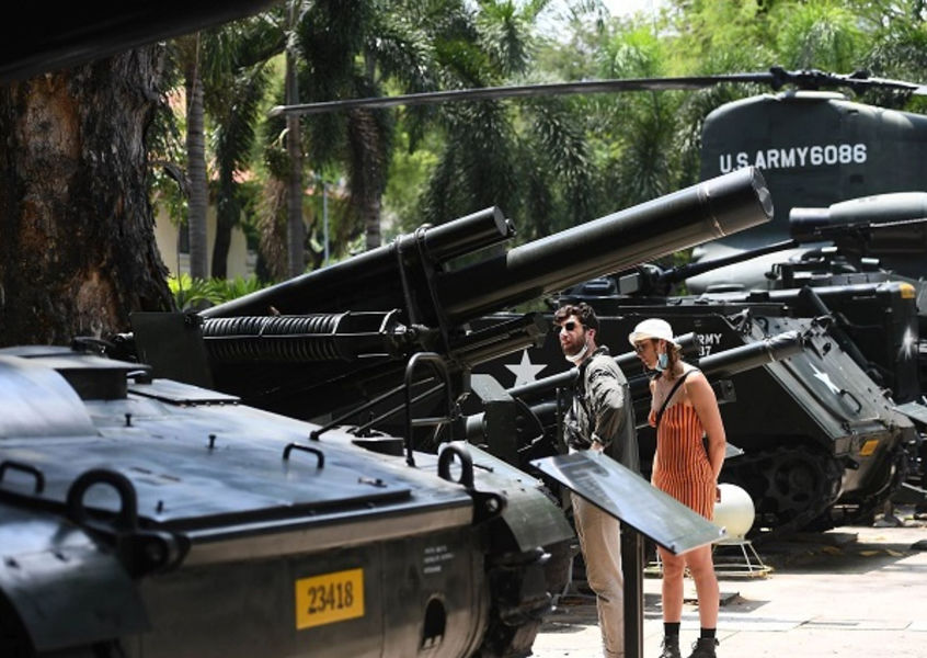 Visitors viewing artillery and helicopter outdoors