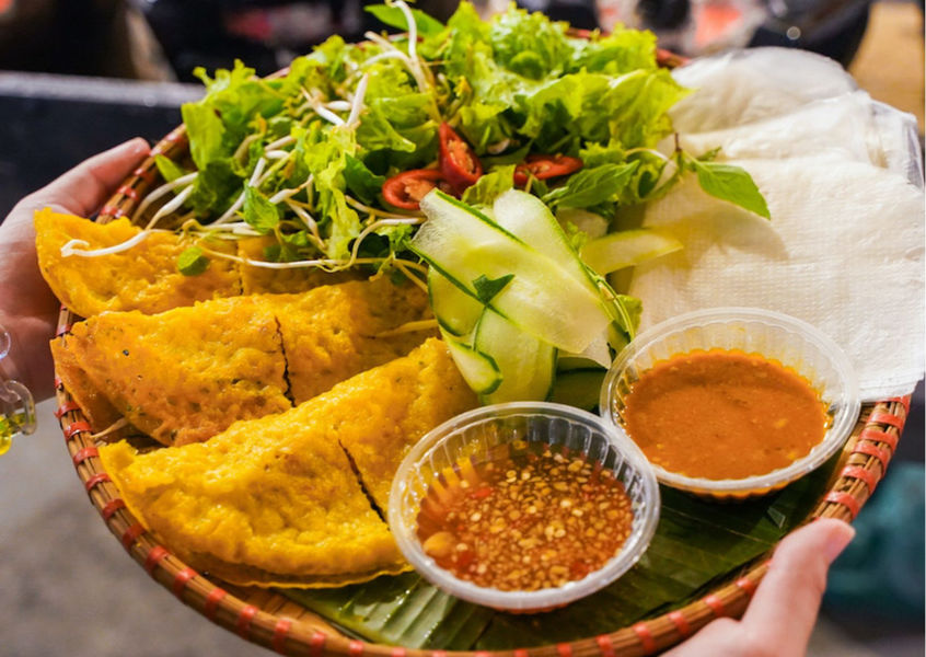 Banh Xeo pancake served with fresh herbs and dipping sauce