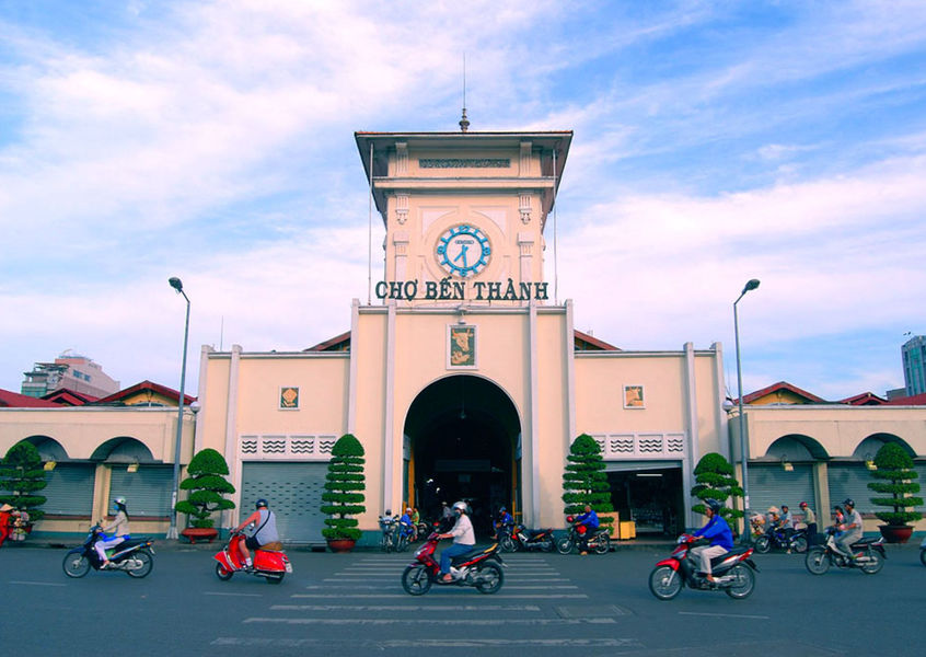 Ben Thanh Market front entrance with clock tower and motorbikes in Ho Chi Minh City