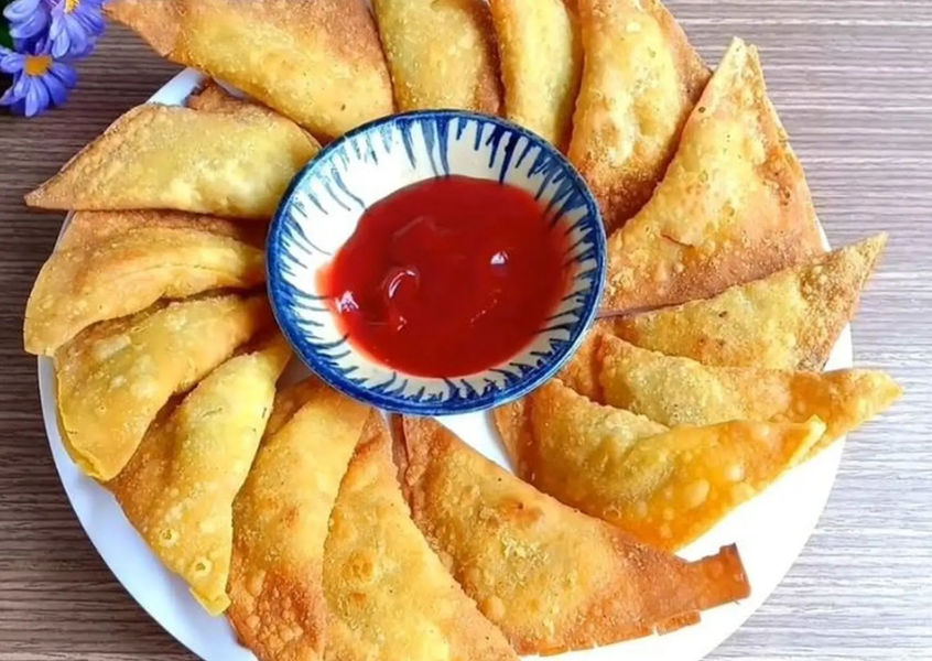 Crispy fried wontons arranged on a plate with dipping sauce