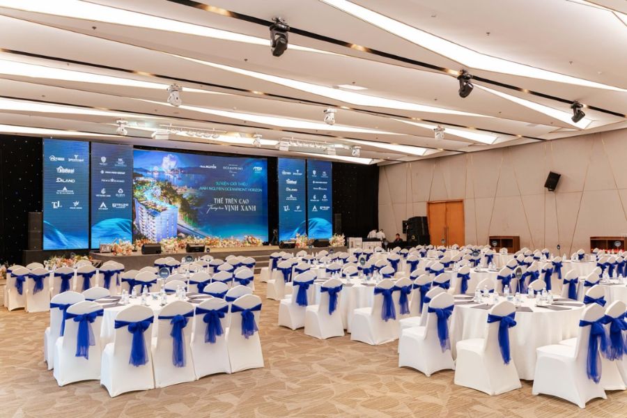 Ballroom gala setup with blue chair sashes and round tables in Nha Trang